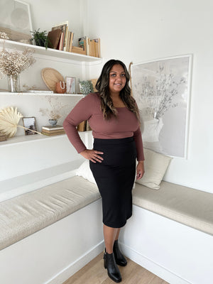 indian woman wearing a long sleeved brown square neck top with black midi skirt and black booties