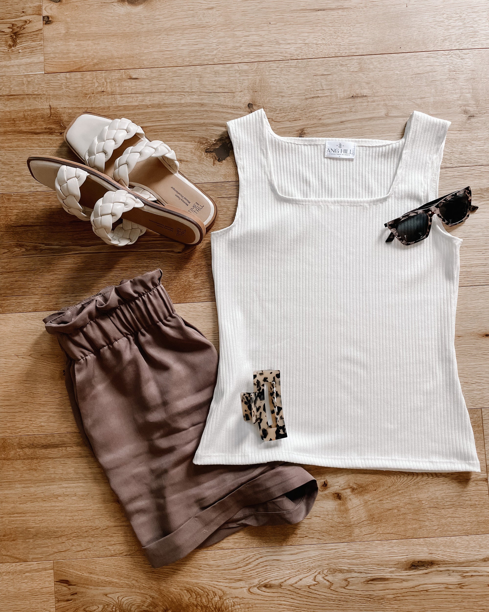 woman wearing white tank top with brown buttons, brown paper bag shorts