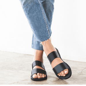 Female model wearing jeans with the Sustainably crafted Ophelia leather slide sandals from Brave Soles in classic black color.