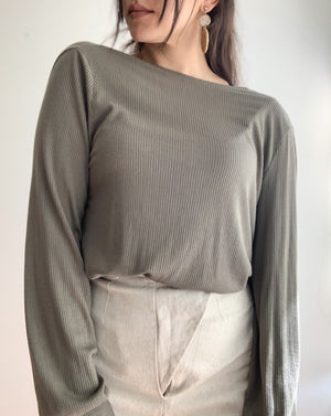 Ribbed reversible wrap top in the colour olive worn with beige pants.