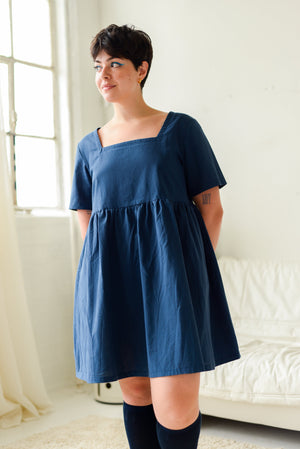 non-binary model wearing dark blue mini dress with square neckline and short sleeves