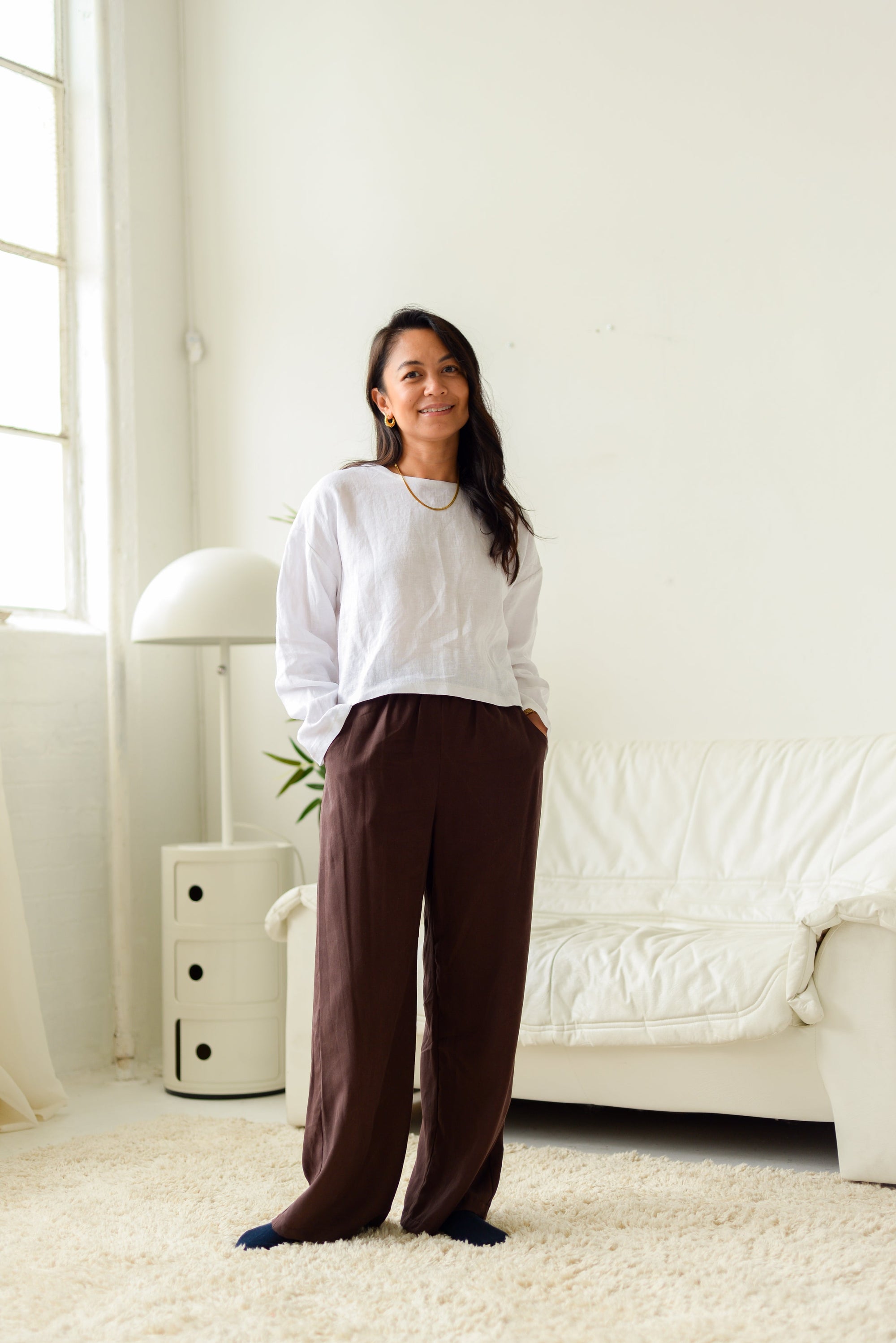 petite woman wearing loose wide leg dark brown pants and a white linen top